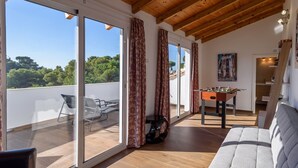 A spacious living area with a sofa, a foosball table, and a balcony with a view of trees. - Villa Matella Vélez-Málaga by Ruralidays (Málaga)