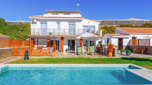 Une maison à deux étages avec une piscine, du mobilier d’extérieur et une vue sur les montagnes.