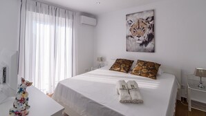 A hotel room with a large bed, two pillows, a painting of a lion, a desk with a lamp, and a decorative sculpture. - Villa Matella Vélez-Málaga by Ruralidays (Málaga)