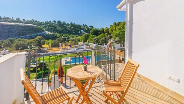 A balcony with a wooden table and chairs, a pool, and a view of the surrounding landscape. - Villa Matella Vélez-Málaga by Ruralidays (Málaga)