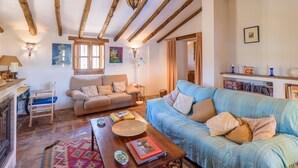 A cozy living room with a sofa, a wooden coffee table, and a fireplace. - Casa Angelica Cómpeta by Ruralidays (Málaga)