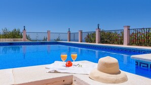 A poolside area with a white towel, two glasses of orange juice, and a straw hat on a stone ledge. - Casa Angelica Cómpeta by Ruralidays (Málaga)