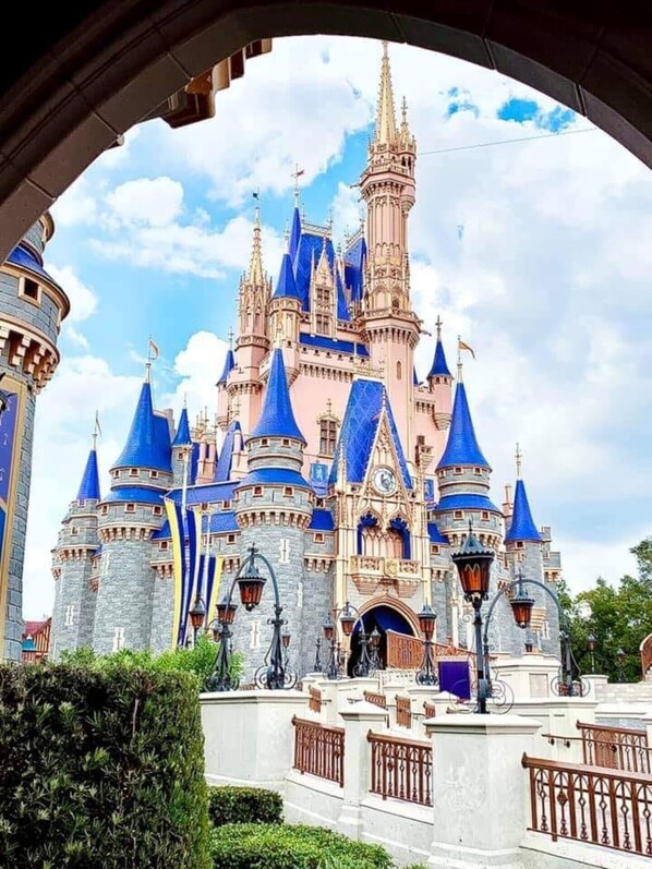 A castle with multiple towers and spires, a large entrance gate, and a well-maintained garden area.