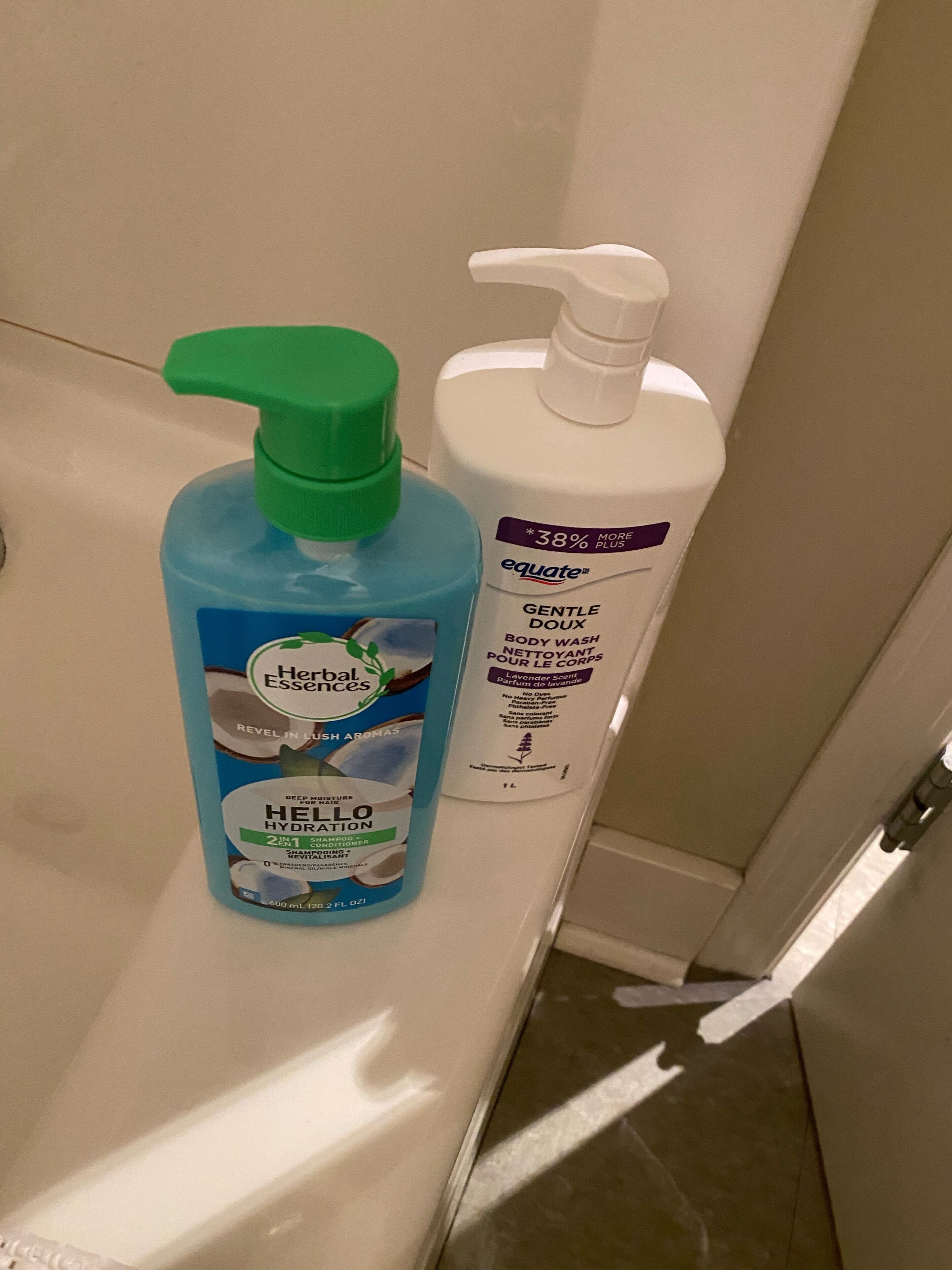 A bathroom with a white countertop. On the countertop, there are two bottles of personal care products.