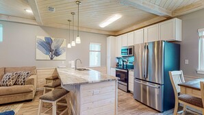 A modern kitchen with a large island, stainless steel appliances, and a wooden ceiling. - Shared Heated Pool, Observation Deck, Golf Cart Included, Pet Friendly (Port Aransas)