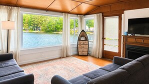 A living room with a large window, a fireplace, a TV, and a surfboard-shaped Wi-Fi sign.
