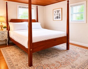 A four-poster bed with a wooden frame, white bedding, and a patterned rug on a wooden floor. - Quiet Lakefront Cabin · Private Dock and Firepit (Bath)