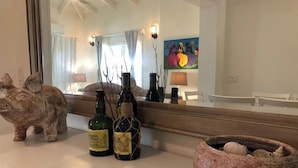 Un meuble-lavabo de salle de bain avec une tirelire, deux bouteilles d’alcool et un bol décoratif.