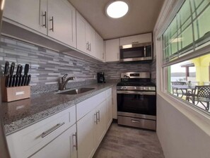 Enjoy meals in the adjacent dining area with a view of the outdoors, accompanied by a compact kitchen featuring a sink, microwave, and double oven.