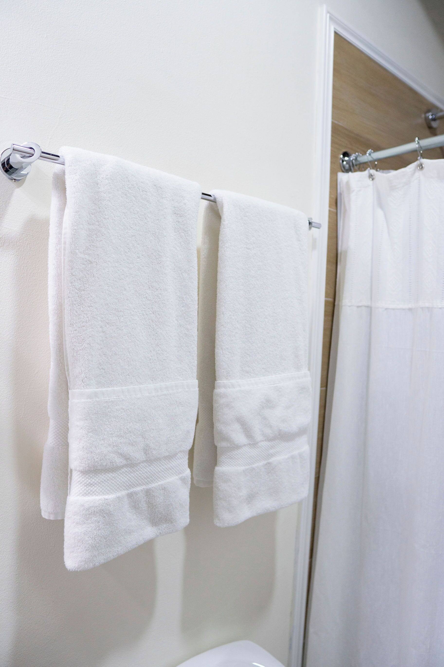 A bathroom with two white towels hanging on a metal towel rack.