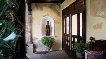 A room with a statue, a wooden door, and a potted plant.