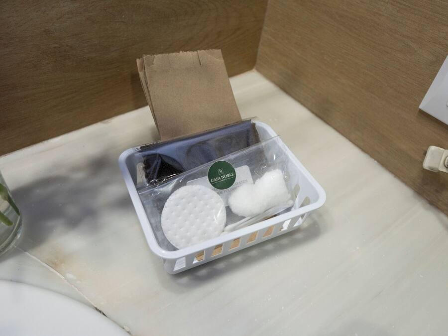 Ein Badezimmer mit einem weißen Waschbecken, einem Glas Wasser, einer Packung Taschentücher und einem weißen Stromkabel.