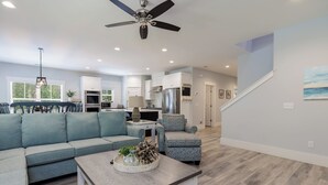 A modern living room with a sectional sofa, a coffee table, and a dining area with chairs.