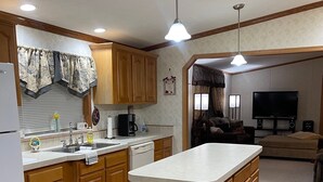 A compact kitchen with wooden cabinets, a central island, and a bar stool.