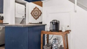Una cocina con encimera azul, una cafetera y un estante con utensilios de cocina.