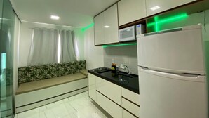 Eine moderne Küche mit weißen Schränken, einer schwarzen Arbeitsplatte, einer eingebauten Mikrowelle und einem Kühlschrank.