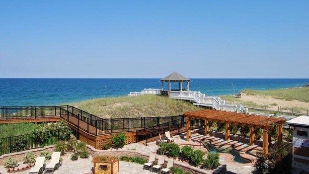 A beachside resort with a gazebo, lounge chairs, and a pool area.