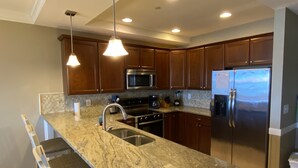 A modern kitchen with granite countertops, stainless steel appliances, and wooden cabinets.