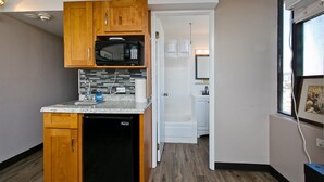 A compact kitchen with wooden cabinets, a built-in microwave, and a dishwasher. - 🗝18th Floor Corner Studio of Hawaiian Monarch w/Awesome Pool in Waikiki (Honolulu)