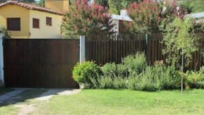 A fenced yard with a grassy area and a building with a yellow facade. - Bambi (La Falda)