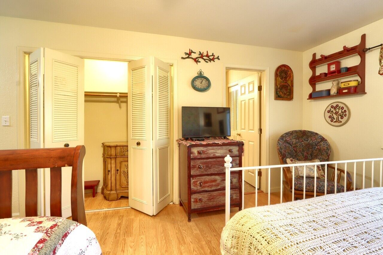 A bedroom with a bed, a dresser, a television, and a chair.