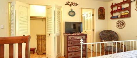 A bedroom with a bed, a dresser, a television, and a chair.