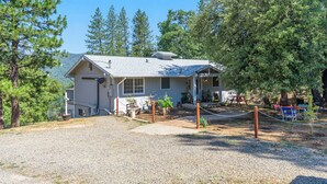 A rustic cabin with a gravel driveway, surrounded by trees and a picnic area. -  Spacious- 11 min to Yosemite toll- 13 guests- 7+ beds, pet- game room- 2000 Ft (Oakhurst)