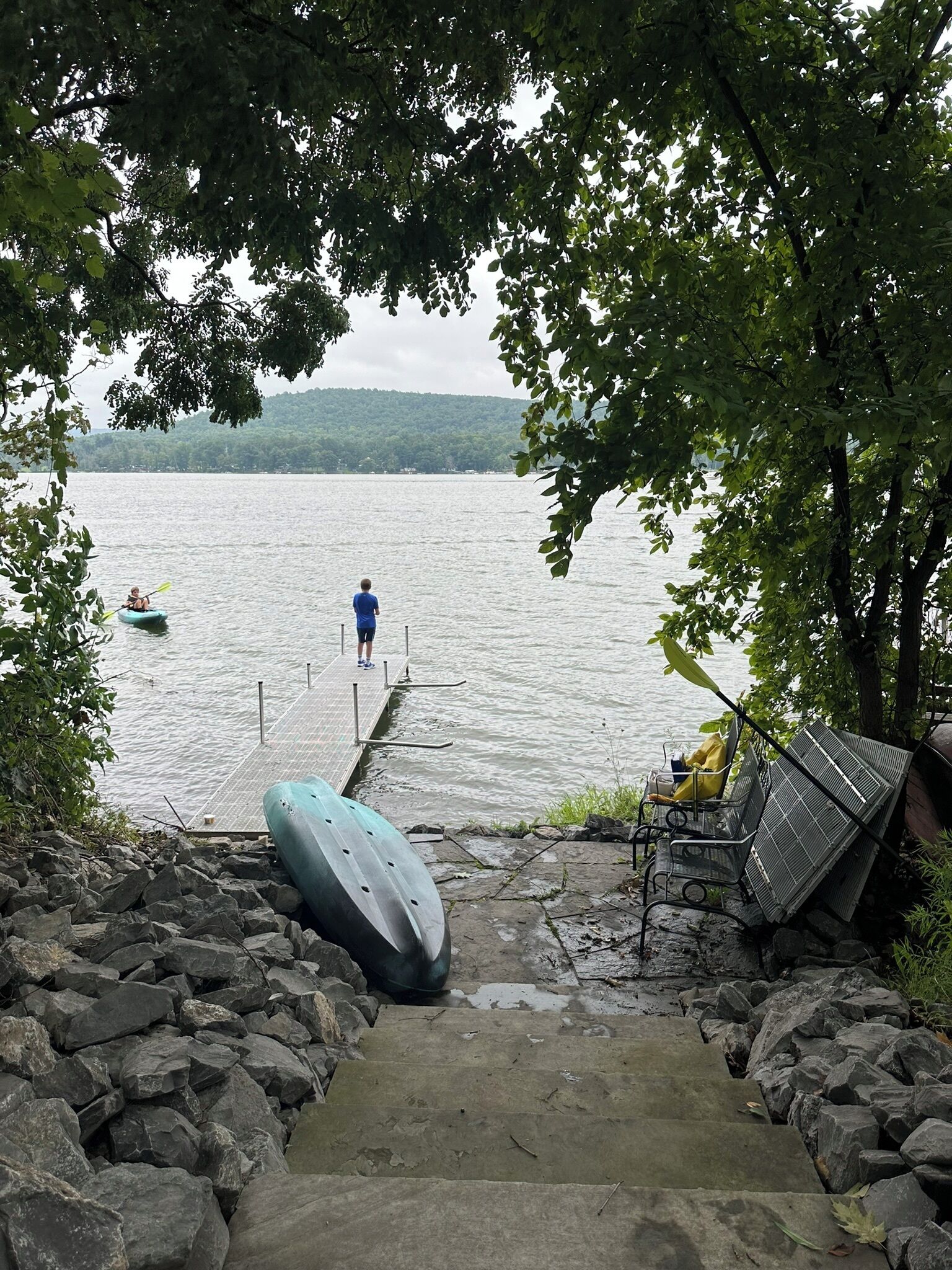 A dock extending into a calm lake with a person standing at the end.