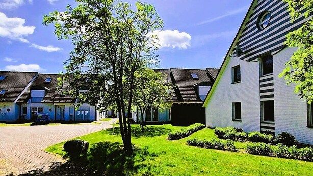 A residential area with modern houses, a paved pathway, and a grassy lawn.
