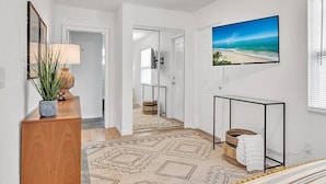 A modern hotel room with a large TV, a wooden console, a patterned rug, and a beach view. - 3-bedroom-2 Full Baths Beach House mnts to Central Beach & downtown (Vero Beach)