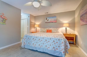 A bedroom with a bed, two nightstands, a ceiling fan, a door, and a wall with a painting. - Bright & sunny 2 bed/2 bath condo in Navarre (Navarre)