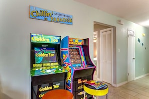 A room with two arcade machines, a sign reading "Chillin' in Paradise," and a door with a light switch. - Bright & sunny 2 bed/2 bath condo in Navarre (Navarre)