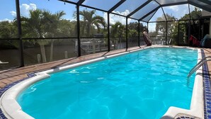 An indoor swimming pool with a clear view of palm trees outside.