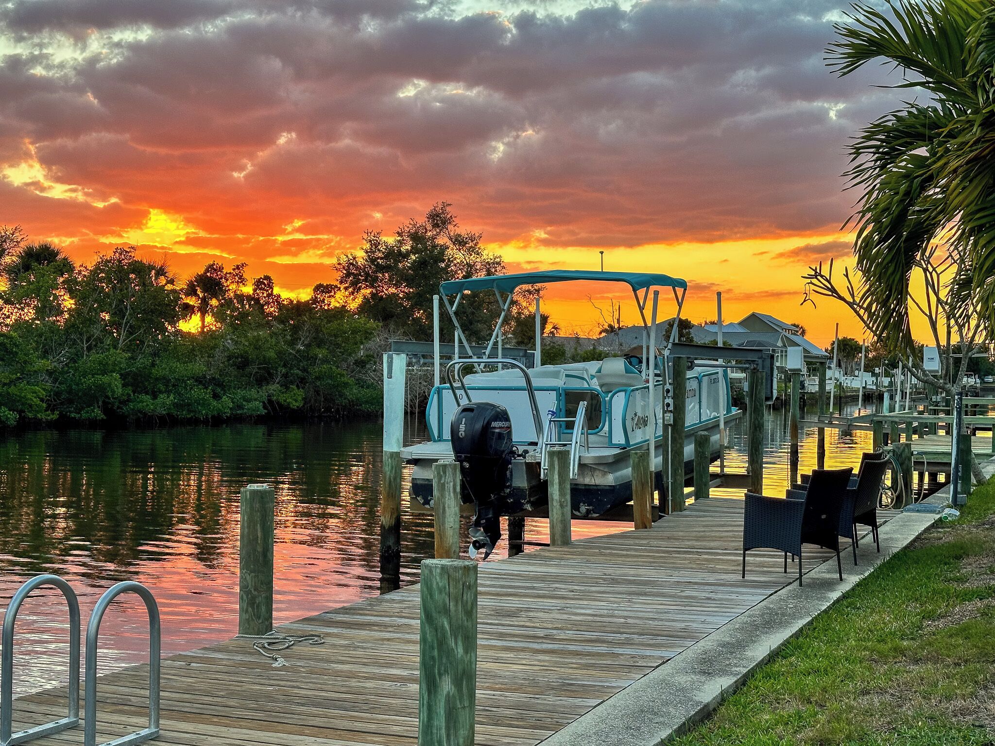A dock with boats, a wooden walkway, and a sunset in the background.