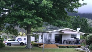 En campingvogn med terrasse, udendørs møbler og en parabolantenne.