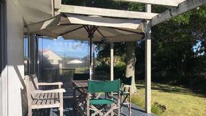 En træterrasse med et pergolaoverdækning, to træstole og et bord.