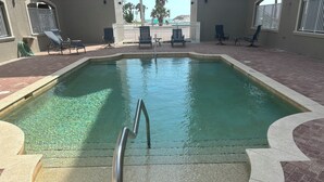 A swimming pool with a metal ladder, surrounded by lounge chairs and a paved deck. - RELAX and Save! Escape on sunny Fort Myers Beach in a 2BR/2BA w/ Pool/ Gulf view (Fort Myers Beach)