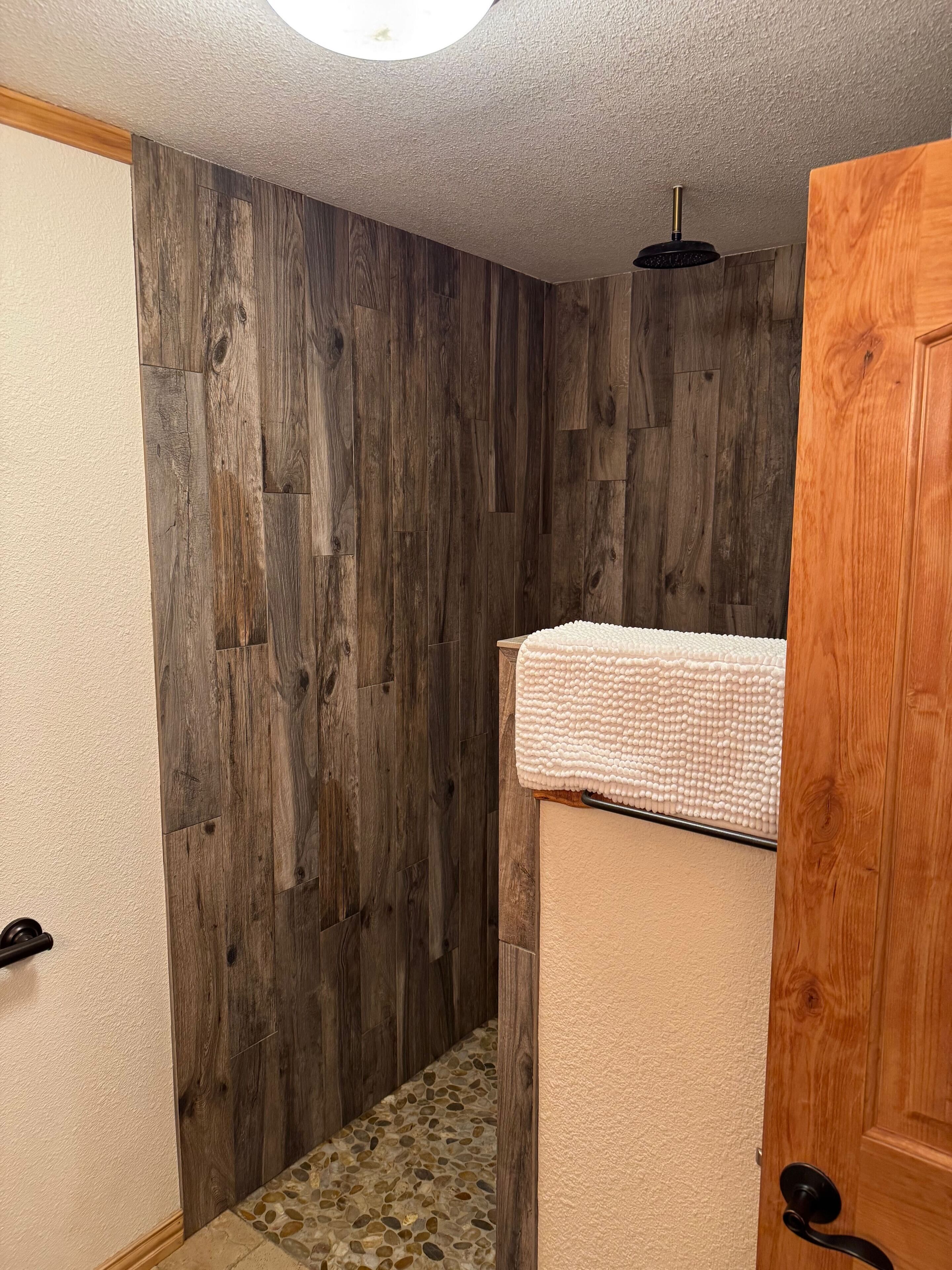 A bathroom with wooden walls, a tiled floor, and a towel on a wooden shelf.