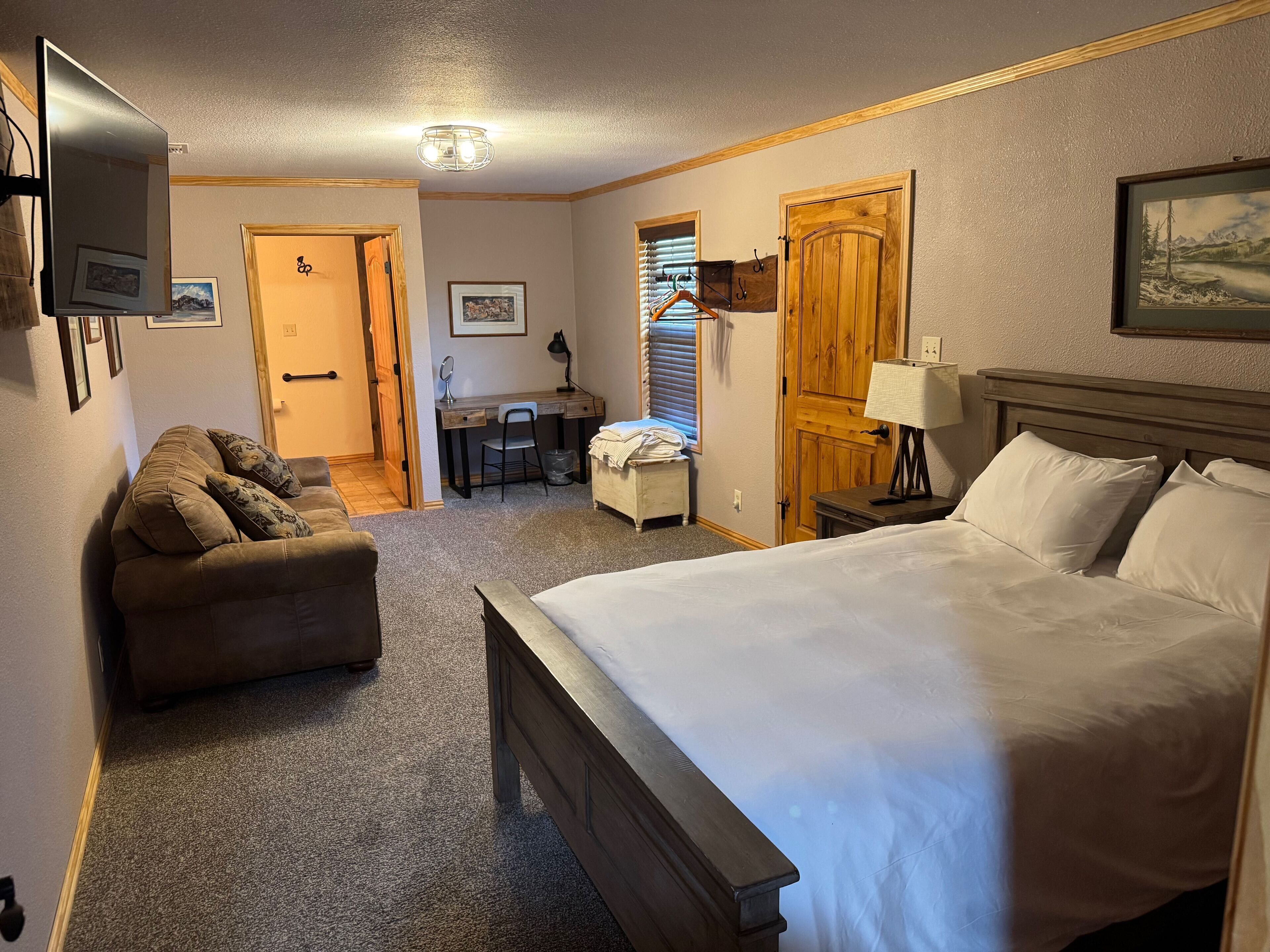 A hotel room with a large bed, a desk, a chair, and a couch.