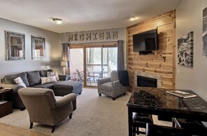 A living room with a couch, armchairs, a coffee table, a fireplace, and a television mounted on a wooden wall. - Skiing , golf or nearby lakes. Schuss has it all! (Bellaire)