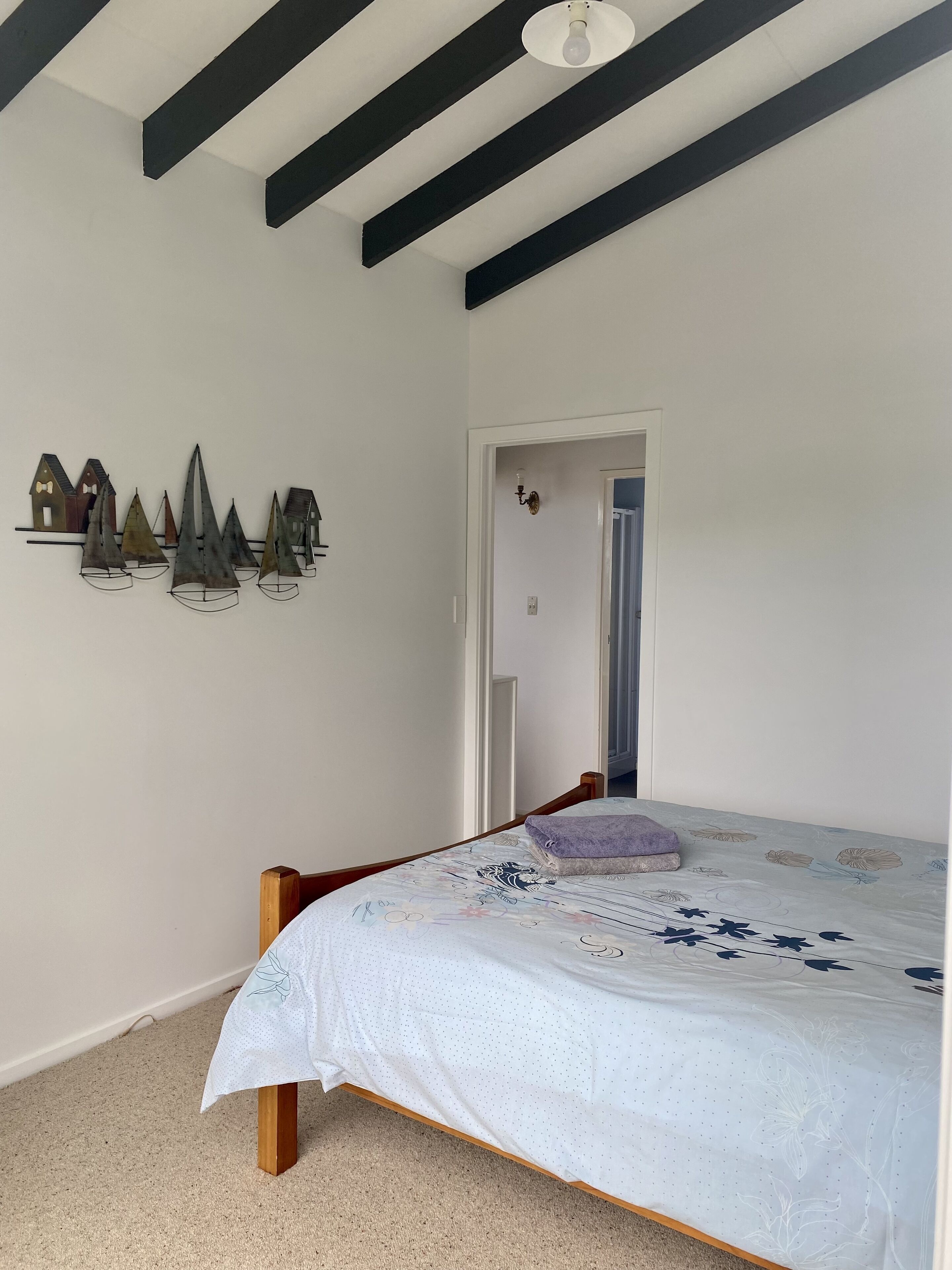 A bedroom with a bed, a door, and a wall with decorative items.