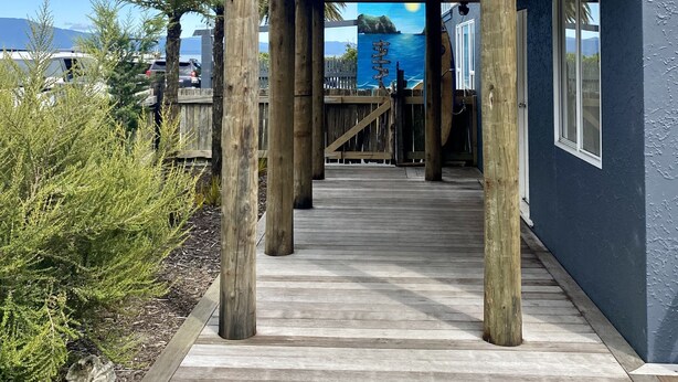 A modern house with a wooden deck, glass balcony, and a view of the ocean. - Totara Bach - just a few meters away from the beach (Tata Beach, Golden Bay) (Tata Beach)