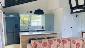 A modern kitchen with a built-in refrigerator, a central island, and a pendant light. - Totara Bach - just a few meters away from the beach (Tata Beach, Golden Bay) (Tata Beach)