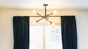 A cozy room with a cushioned bench, a wooden table, and a modern light fixture. - Jackalope Motor Lodge (Pinedale)