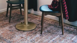 A room with a round table, two chairs, a hanging light fixture, and a window with curtains. - Jackalope Motor Lodge (Pinedale)