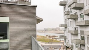 Ein modernes Gebäude mit einem Balkon, der auf einen Fluss und einen Park blickt.