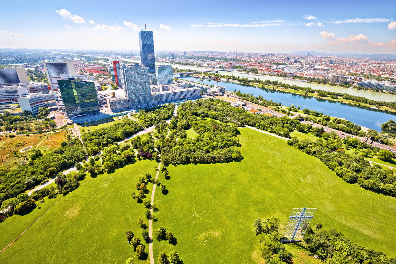 Eine Vogelperspektive auf eine Stadt mit modernen Wolkenkratzern, einem Fluss und Grünflächen.