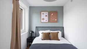A bedroom with a bed, a nightstand, a lamp, and two framed pictures on the wall. - Luxe Oerlikon 3.5 Room w/ Balcony, 1min to Train Station, by Blueground (Zurich)