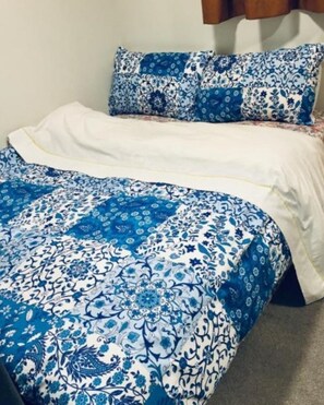 Comfortable bed with a floral patterned bedspread and matching pillows.