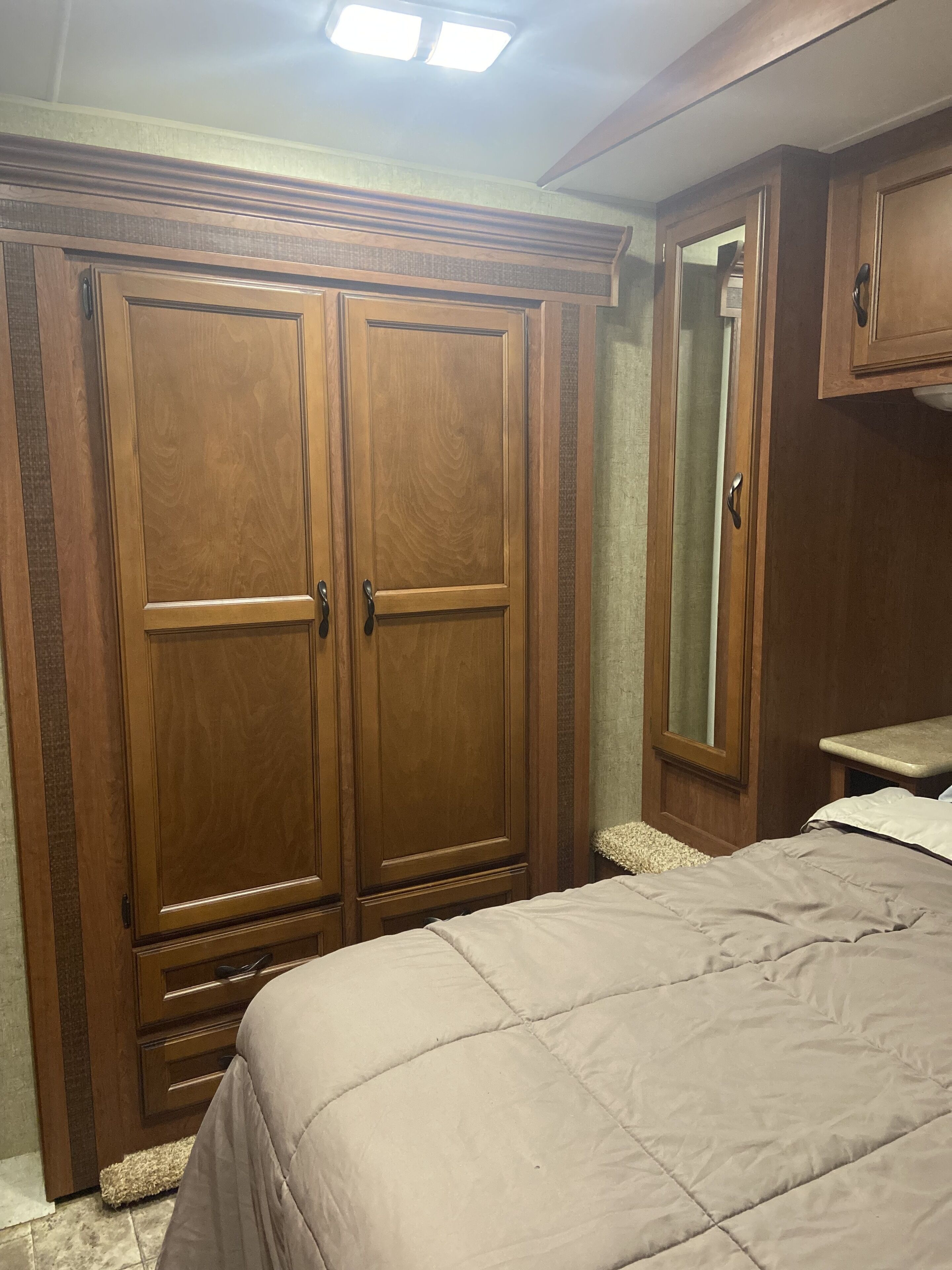 Een slaapkamer met een grote kledingkast, een bed en een spiegel.